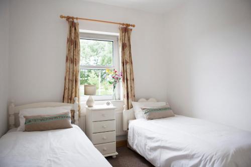 2 Betten in einem Schlafzimmer mit Fenster in der Unterkunft Inviting 4-Bed House in Strokestown in Grange