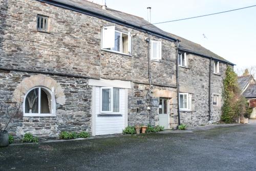 an old stone house with white doors and windows at Lower Trengale Farm Holiday Cottages in Liskeard