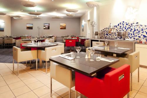a restaurant with tables and red chairs in a room at Novotel Lille Centre Gares in Lille
