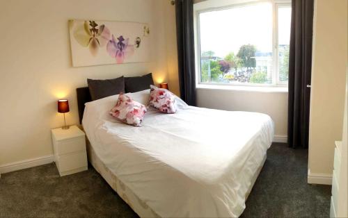 Un dormitorio con una cama blanca con almohadas rosas y una ventana en Balcony Apartment near Skegness Beach & Town en Skegness