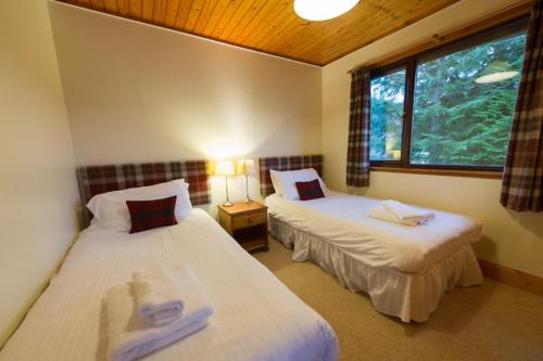 two beds in a room with a window at Eagle Lodge with stunning loch and mountain view in Crianlarich