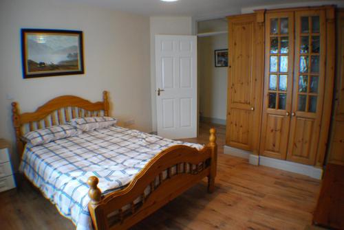 a bedroom with a wooden bed and wooden floors at Cosy 2-Bed Cottage in Sligo in Enniscrone