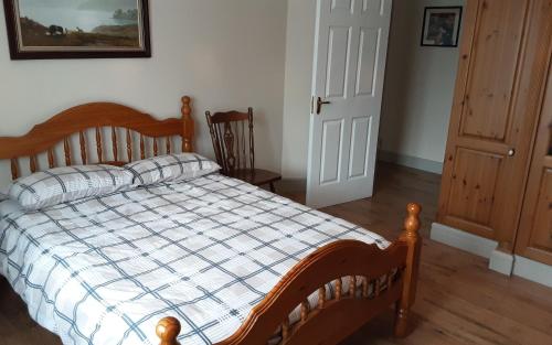 a bedroom with a wooden bed with a checkered blanket at Cosy 2-Bed Cottage in Sligo in Enniscrone