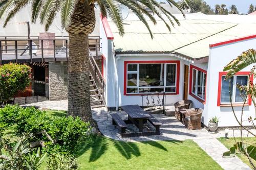 una casa con una palmera y un banco en Stay Cleverly Self Catering Apartments en Walvis Bay