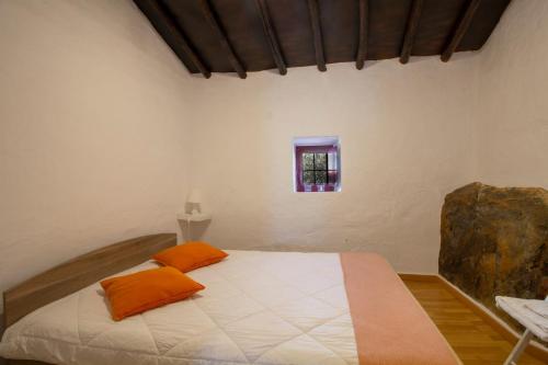 um quarto com uma cama com almofadas laranja e uma janela em Recanto do Alqueva em Monsaraz