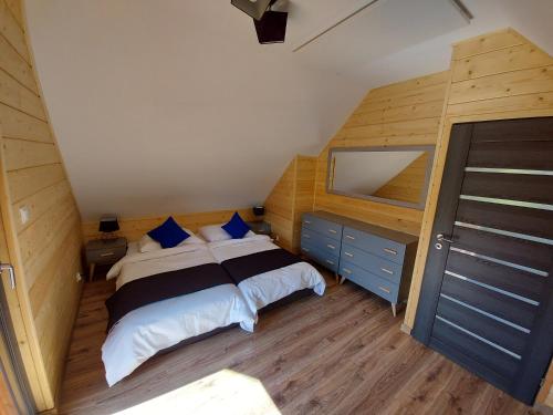 een slaapkamer met een bed met blauwe kussens en een spiegel bij Osada Orlica 3 in Lasowka