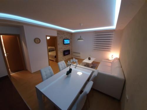 ein Wohnzimmer mit einer weißen Couch und einem Tisch in der Unterkunft Apartman Teodora in Kopaonik