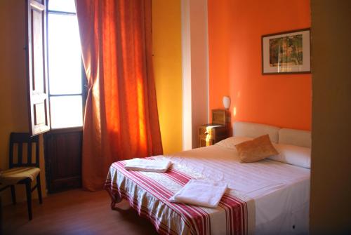 a bedroom with a bed with orange walls and a window at Hotel Europa in Perugia