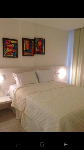 a bedroom with a white bed with three pictures on the wall at WATER FRONT in Maceió