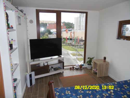 a living room with a flat screen tv and a large window at Departamento 1D 1B, Puerto Montt in Puerto Montt