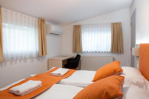 a hotel room with two beds and a desk at Hotel Gostilna Vovko in Novo Mesto