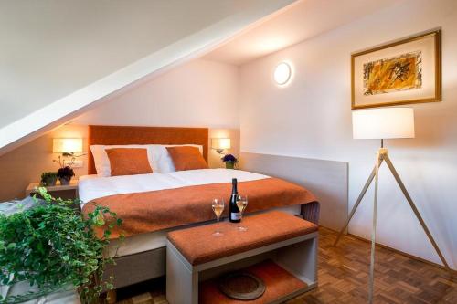 Un dormitorio con una cama y una mesa con copas de vino. en Hotel Gostilna Vovko, en Novo Mesto