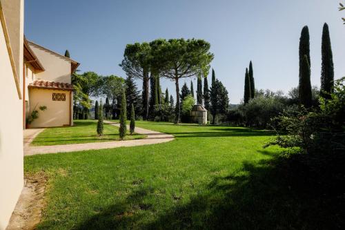 a green yard with trees and a house at Tenuta Tegolato in Barberino di Val dʼElsa