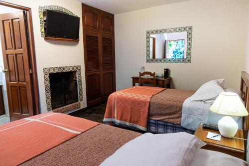 a hotel room with two beds and a fireplace at Hotel San Jorge by Porta Hotels in Antigua Guatemala