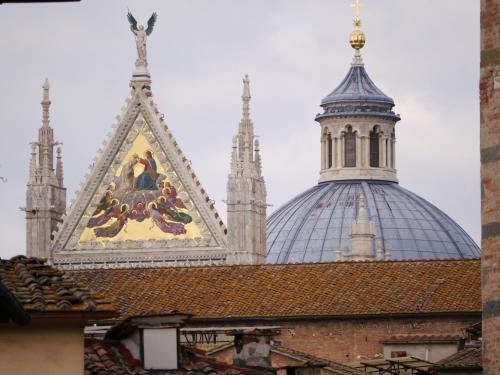 a building with a church steeple and a painting on the roof at Albergo Tre Donzelle in Siena