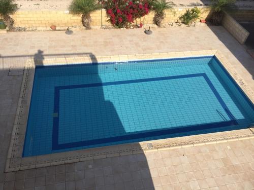 a blue swimming pool with a shadow of a man at Beautiful spacious 2-Bed Apartment in Xylofagou in Xylophaghou