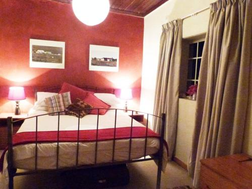 a bedroom with a bed with a red wall at Cosy 6 Person Cottage with Mountain View in Barrydale