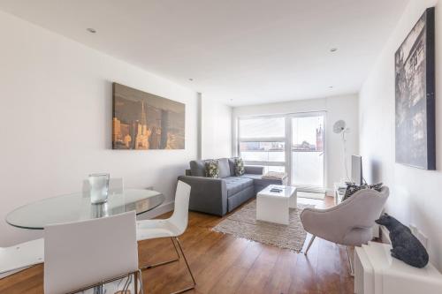 a white living room with a table and a couch at Luxury 2-Bed Flat parking near Tube and Emirates in London