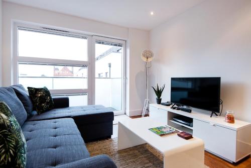 a living room with a couch and a tv at Luxury 2-Bed Flat parking near Tube and Emirates in London