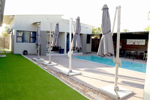 a row of closed umbrellas next to a pool at Phudzi Hotel in Letlhakawe