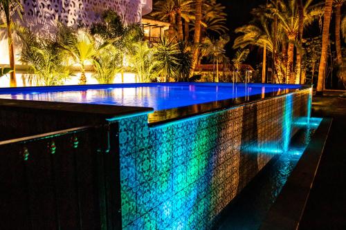 einen Pool in der Nacht mit blauen und grünen Lichtern in der Unterkunft Eden Meloneras by TAM Resorts in Maspalomas
