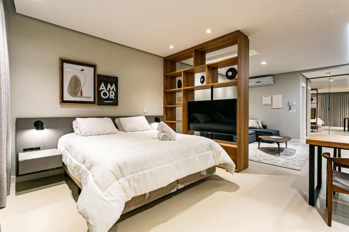 a bedroom with a large bed and a living room at WI-FI 350MB | Foodhall | 450m do Shopping #CA14 in Florianópolis