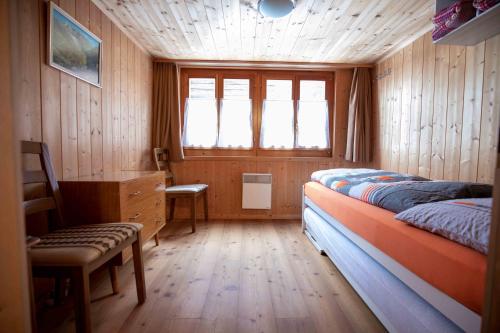 a bedroom with a bed and a desk and a window at Alpensonne in Reckingen - Gluringen