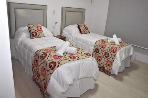 Cette chambre comprend deux lits, une table et des chaises. dans l'établissement Ambientes de la Patagonia, à Winifreda