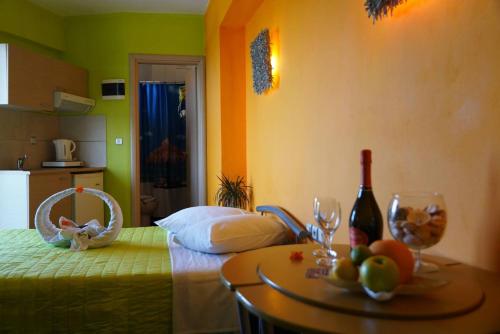 Lilalo Ηotel في باراليا كاتيرينّيس: غرفة نوم مع سرير وطاولة مع كؤوس للنبيذ
