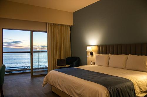 a hotel room with a bed and a view of the ocean at Varali Grand Hotel in Mazatlán