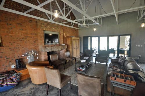 ein Wohnzimmer mit Möbeln und Ziegelwand in der Unterkunft Tula Baba Game Lodge in Brits