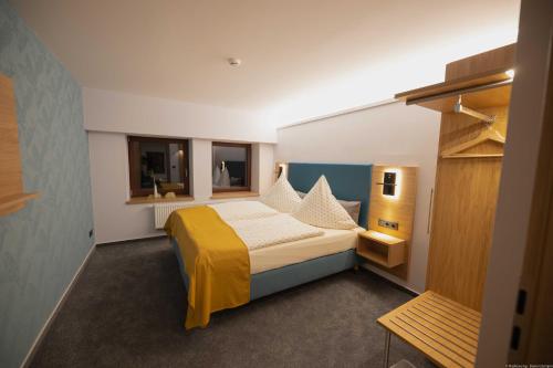 a bedroom with a large bed with a yellow blanket at Landhotel Zur Guten Einkehr in Bautzen