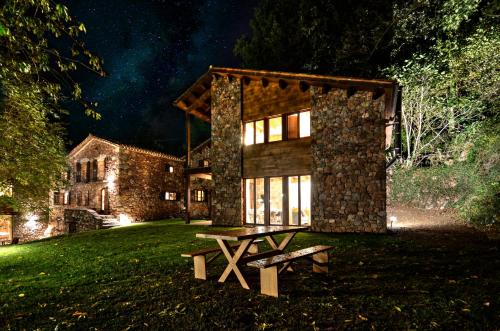 una casa con una mesa de picnic delante de ella por la noche en Masias de Rocabruna, en Rocabruna