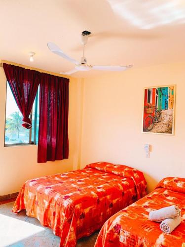a bedroom with two beds and a window with a fan at Hotel Sociedad y Maristas in Tecolutla