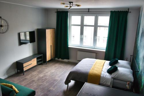 a bedroom with a bed and a window with green curtains at Pośród Drzew Studio Świętojańska Gdynia in Gdynia