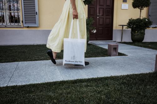 una mujer caminando por una acera con una bolsa de compras en Residenza San Vito, en Calamandrana