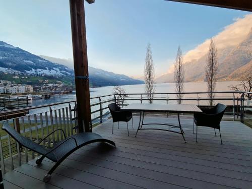 a table and chairs on a deck with a view of a lake at Walensee House & Apartments in Unterterzen