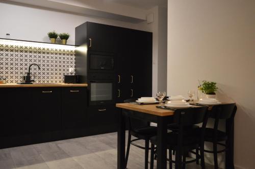 a kitchen with a wooden table and black cabinets at Apartament M&I in Koszalin