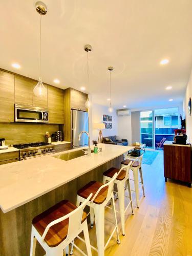 a kitchen with a large counter with chairs around it at Modern Ballard Townhouse - 92 Walkscore & Rooftop! in Seattle