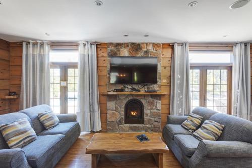 a living room with two couches and a stone fireplace at Royal Laurentien in Mont-Blanc