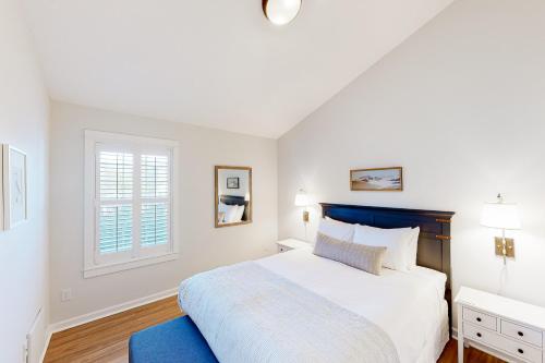 een witte slaapkamer met een groot bed en een raam bij The Surfbird in Pacific City