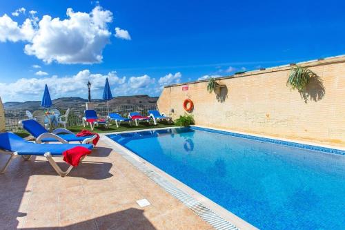 una piscina con sillas azules junto a un edificio en Ta Danjela 4 bedroom Villa with private pool, en Xagħra