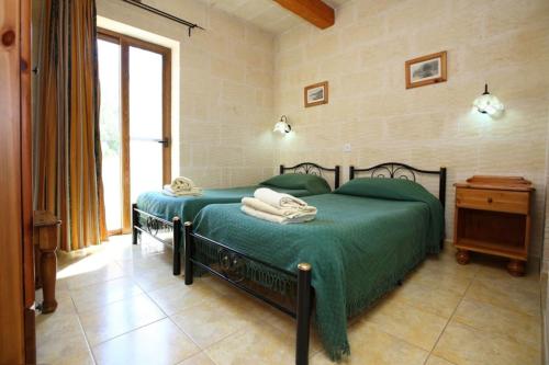a bedroom with a green bed and a window at Ta Danjela 4 bedroom Villa with private pool in Xagħra