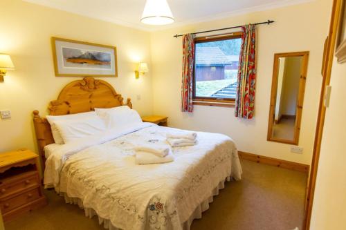 a bedroom with a large bed and a mirror at The Raven in Crianlarich