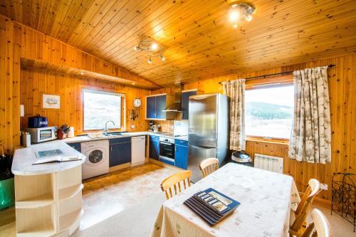 a kitchen with wooden walls and a table in a room at Raven Lodge with beautiful views of Loch Dochart in Crianlarich
