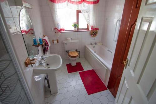 a bathroom with a sink and a toilet and a tub at Stunning 3-Bedroom House with Private Garden in Carracastle