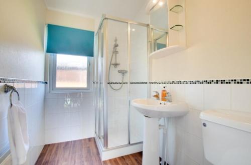 a white bathroom with a shower and a sink at Stunning 3-Bed Hot Tub Lodge Northumberland in Felton
