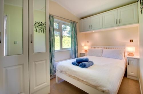 a bedroom with a white bed with blue towels on it at Stunning 3-Bed Hot Tub Lodge Northumberland in Felton