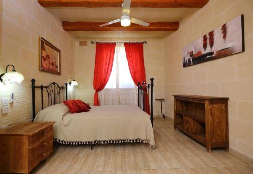 - une chambre avec un lit et une fenêtre avec des rideaux rouges dans l'établissement Villa Savona 3 Bedroom Villa with private pool, à Ix-Xagħra