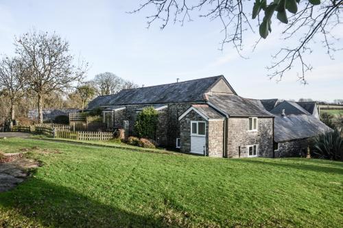 an old stone house with a green yard at Lower Trengale Farm Holiday Cottages in Liskeard